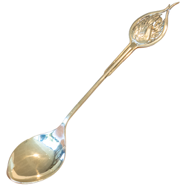 Decorative gold spoon with a leaf-shaped handle on a white background