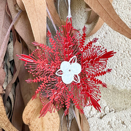 Red decorative bottlebrush flower with a white center on a textured beige background