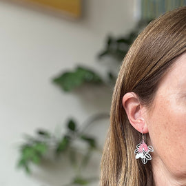 Close-up of a woman wearing floral earrings with a blurred indoor background