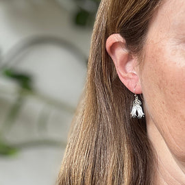 Close-up of a person wearing a silver earring with a blurred background