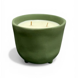 Green ceramic pot with a white candle inside on a white background