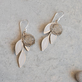 Silver floral earrings on a textured gray surface