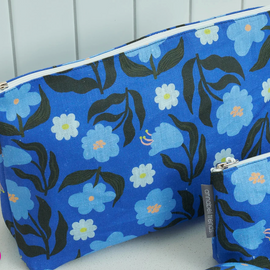 Blue floral-patterned pouches with white zipper on a light gray background