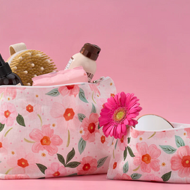 Floral-patterned makeup bag with cosmetic items on a pink background