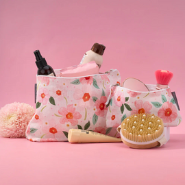 Floral-patterned cosmetic bags with various items on a pink background