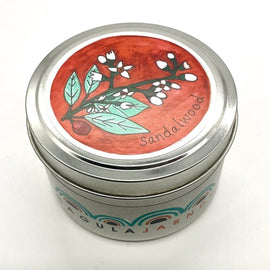 Candle in a tin container with a decorative lid featuring sandalwood design on a white background