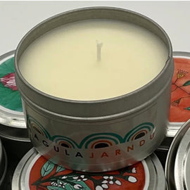 Candle in a decorative tin with colorful labels in the background