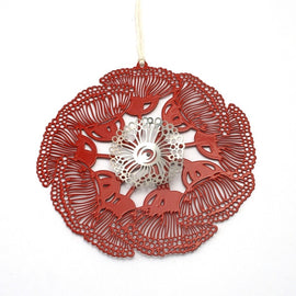 A round, red stainless steel Christmas ornament with a floral pattern, featuring a powder-coated finish and tied with string.